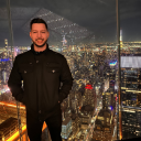 Gustavo standing with a city behind