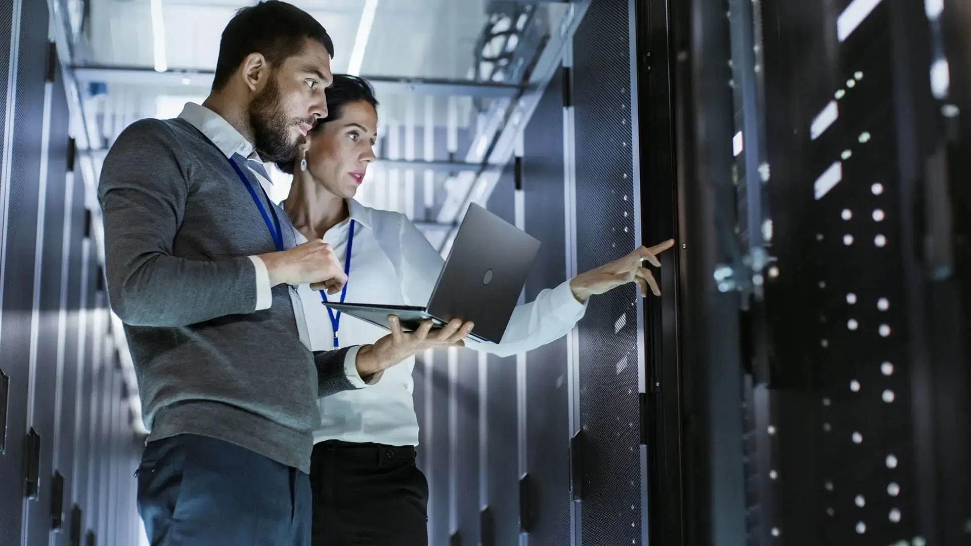 two people looking a server with computers in hand
